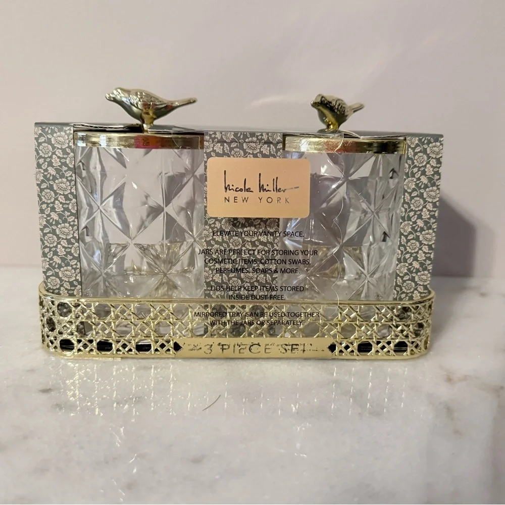 two-piece glass storage jar set with a gold bird lid and decorative tray.
